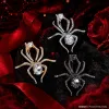 Three vintage crystal spider brooches, silver, gold and black alloy pins, Muslim-style white display stand undefined